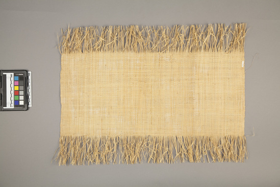 Hearst Museum object titled Woven mat, accession number 5-14963, described as Mat: small rectangular mat from raffia palm leaves; fringed on two longer edges. Mat used as money and sometimes clothing. Length 57.3 cm. Width 42.5 cm. (fringe included)