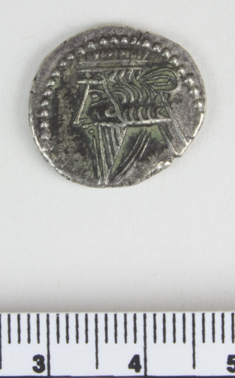 Hearst Museum object titled Coin, accession number 9-22786, described as Parthian coin, silver, some tarnish, recto: outline style face in profile facing right, triangle beard, wavy hair, 3 bands at neck, diadem on head with loop sticking out back and end hanging down, curved row of dots overhead; verso: figure sitting with a bow surrounded by text.