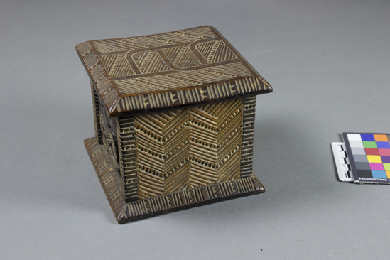 Hearst Museum object 6 of 8 titled Carved wooden box, accession number 11-42799a,b, described as Box and lid, wood, carved in relief, geometric pattern on lid and two sides of box, facial image carved on other two sides of box; tan and brown.