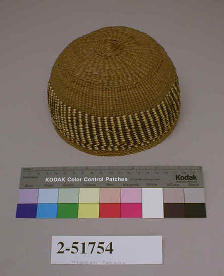 Hearst Museum object titled Hat, accession number 2-51754, described as Could also be cap. Made from bowl-shaped twined basket with deep design band on body of alternating brown and straw-colored vertical stripes.