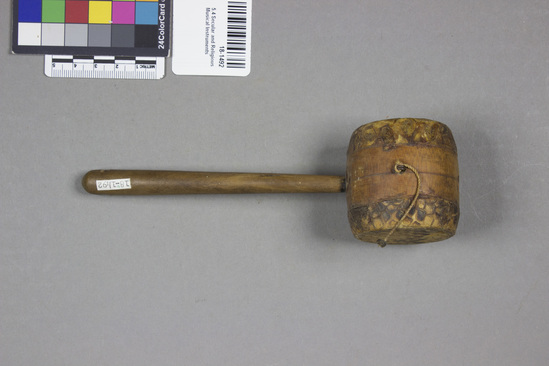 Hearst Museum object 2 of 2 titled Rattle, accession number 18-1492, described as Rattle. Wood, snakeskin cover on ends of drum shaped head, small metal loops with remnants of cotton string on sides; handle has a hole at end. length - 17.5 cm.; head, diam. - 4.4 cm. Collector states that specimen is "a vendor's rattle.