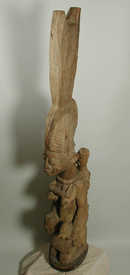 Hearst Museum object titled House post, accession number 5-14494, described as wooden house post, Ekiti style; woman offering a cock. H = 138 cm. “Arowogun Osi” - 84” w/ stand. Purchased 1965, #3139, $3500 less discount, plus tax; $36.80 shipping. 55.0” ; 84” with stand.