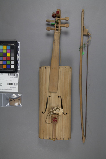 Hearst Museum object titled Fiddle and bow, accession number 10-1969a,b, described as A) Fiddle of bamboo and wood, 4 string, red and white wool tassels, 19½ inches long B) Bow, made of wood, 20½ inches long