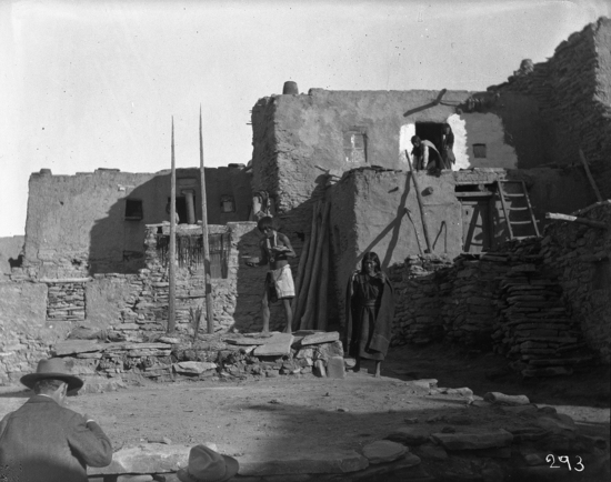 Hearst Museum object titled Black-and-white negative, accession number 15-293, described as Priest taking food from woman and about to take it into the Antelope kiva for the men below; white photographers in foreground.