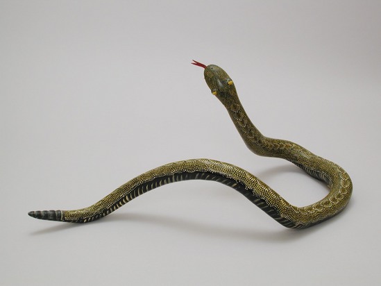 Hearst Museum object titled Snake figurine, accession number 3-26855, described as Snake; made of twisted root; black lacquer background painted over with yellow and green paint in small dots on top and stripes on bottom (in snake-skin pattern); plastic eyes, leather thong painted red for tongue; fangs of bone; max. overall L 53.5 cm, H 24 cm