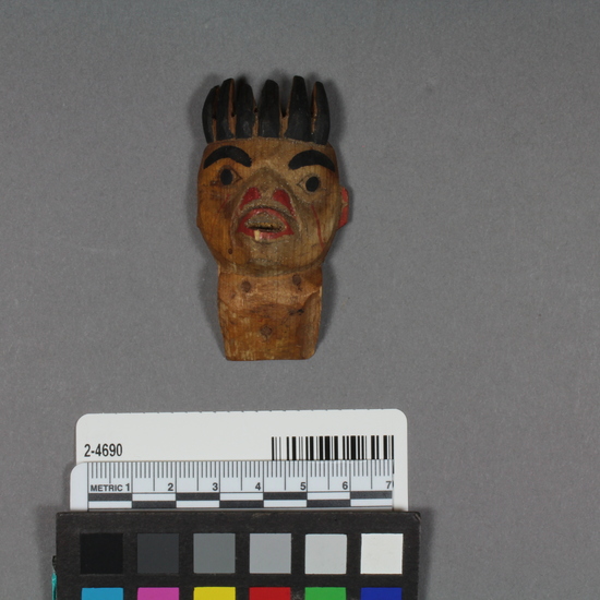 Hearst Museum object titled Totemic carving, accession number 2-4690, described as Small, wooden, of head of a man. Part of a larger carving. Represents doctor (shaman) at practice, wearing bear claw crown (fide Bill Holm).