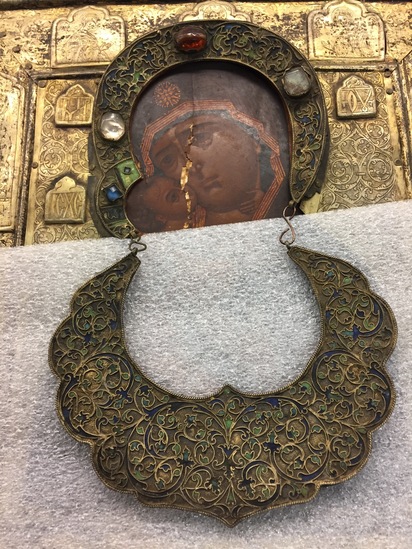 Hearst Museum object 3 of 49 titled Icon, accession number 7-3541, described as Icon of “Our lady of Vladmir”; Virgin and Child in tempera and gesso on wood; gilded silver basma; cloisonne halo with cloisonne collar pendant; halo has glass and amber (?) ornamentation; Virgin’s face damaged; height 30.2 cm, width 26 cm.