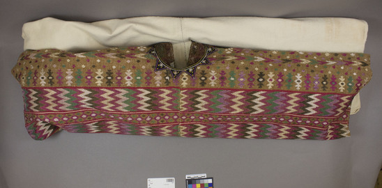 Hearst Museum object 3 of 3 titled Huipil, accession number 3-66, described as Woman’s shirt (huipil); 3-66 lower part white cotton plain weave; upper part brown cotton brocaded in brown, green, lavender, reds, greens and whites; neck bound and embroidered on black ribbon; approximately 1 m wide, 104 cm long Brown is the natural color of the variety of the cotton.