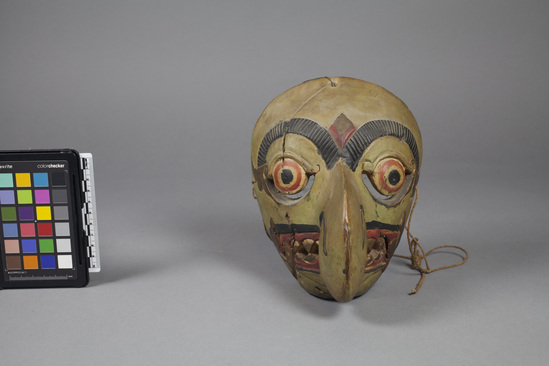 Hearst Museum object 2 of 4 titled Mask, accession number 18-1193, described as Mask, wood, carved and painted; large hook nose and pointed teeth; green, gold, black and red. Used in dance. 18.5 cm.