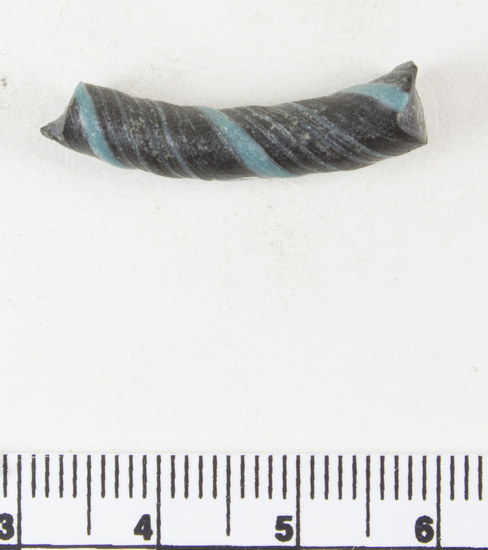 Hearst Museum object 4 of 6 titled Bracelet fragment, accession number 9-8049, described as Glass bracelet frag.; opaque black, twisted, curved rod w/ blue spiral; 27 x 7 mm.