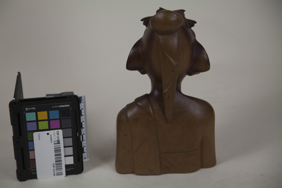 Hearst Museum object 3 of 8 titled Bust, accession number TEMP 2018.998, described as carved wooden female bust (head) signed Sinpar. 9.5"h with long hair pinned up; she wears a headdress, earrings, and strapless garment with cloth over her left shoulder; bust stops at waist and elbows; on bottom is carved "Io Bc. Kp SIMPAR, SANUR., BALI."; "6250" written in black pen on bottom.