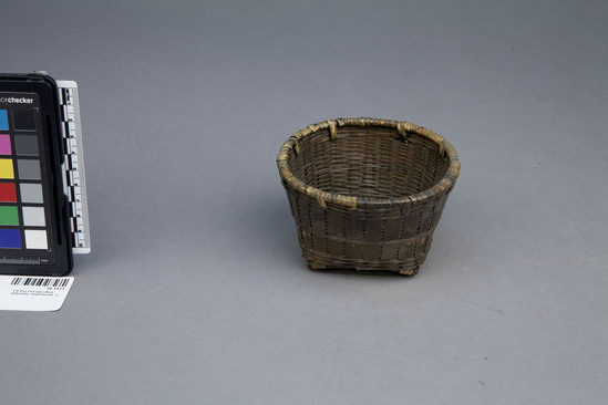 Hearst Museum object 2 of 2 titled Basket, accession number 10-1311, described as Wicker basket with checker bottom of bamboo; dark brown; square bottom; round top; 4 1/4 2dia. x 2 5/8”hi.