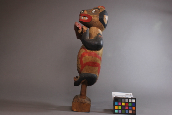 Hearst Museum object titled Bear and fish carving, accession number 2-4798, described as Wooden carving of a standing bear holding a fish (dog salmon); yellow cedar;  inlaid abalone teeth, eyes, and nostrils. Painted red and black. "The bear can be recognized by his short ears." Remarks by Charles Brown.