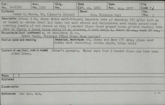 Documentation associated with Hearst Museum object titled Dress, accession number 2-61591, described as Two mountain sheep skins self-fringed; separate yoke of deerskin (?) with fur left on as tassel in center front and back; red wool stroud and varicolored glass seed beads around neck opening; panels of red stroud at hem; two pendant discs faced with seed beads with cotton cloth backing from yoke in front; 3 large brass bells (2 on sleeves, 1 back hem).