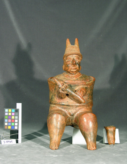 Hearst Museum object titled Figurine, accession number 3-15965, described as Seated warrior with armor for body and helmet, holding ciedgel --hollow, clay with reddish slip, 24 inches high.