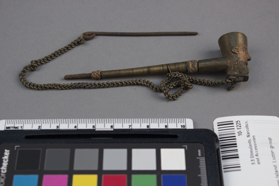 Hearst Museum object 2 of 2 titled Pipe with cleaner, accession number 10-1225, described as Brass pipe with iron stem and attached chain; iron pin; bowl in form of human face; 4 3/8” L. (iron mouthpiece partially rusted away)