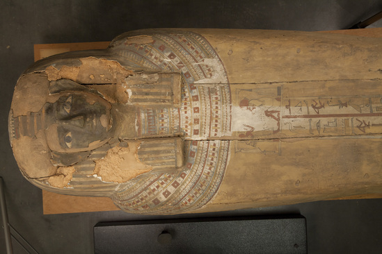 Hearst Museum object 50 of 167 titled Coffin, accession number 6-19912, described as Wooden anthropoid coffin. Inscription running down center of lid. Determined by Kea Johnston to probably be the outer coffin of Iwefaa (6-19928, 12-11039). According to Kea Johnston, "This coffin belonged to a man named Iwefaa, whose name is inserted in the middle of the spells written in the two columns on the front. This coffin is likely the outer coffin for PAHMA 6-19928 based on the similarity of the owner's name, unusual costume, and the paleography of the inscription. Both coffins were purchased on the antiquities market by George Reisner for Phoebe A Hearst. However, stylistically, they are very similar to a set of coffins known to have come from the site of Akhmim, which was excavated in the 1880s by Gaston Maspero, and which has heavily looted for the antiquities market during this decade." "The pectoral vignette between the text and the collar shows the deceased standing before squatting baboon and is the source of our logo. The hieroglyph for 'sky' is above their heads, and the side borders are formed by a pyramid and the symbol for the West.