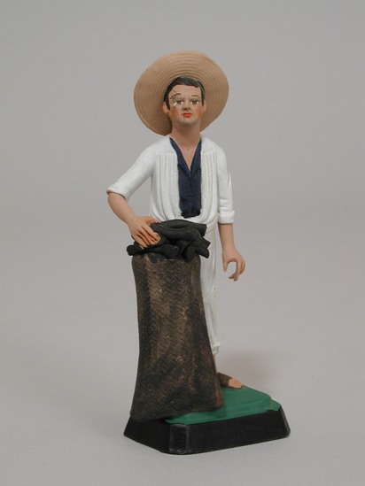 Hearst Museum object titled Figurine set, accession number 3-15702, described as Figurine, ceramic, bisque fired, handpainted; male charcoal vendor in white outfit, charcoal bag in from, on rectangular base; H 13.8 cm