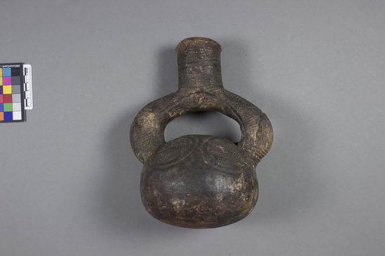 Hearst Museum object titled Bottle, accession number 5-2328, described as Gray-black stirrup spouted bottle, circular designs incised and filled with dentate stamping.