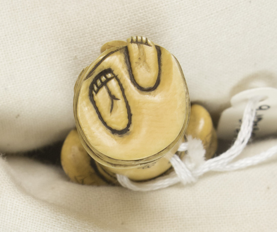 Hearst Museum object titled Netsuke, accession number 9-18785, described as Netsuke; figure of standing woman in flowing robe, with hands placed on top of head as though fixing coiffeure; signature on back of robe; H 5.6 cm X W 2.2 cm