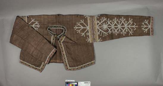 Hearst Museum object 2 of 3 titled Suit and bag, accession number 10-3460a-c, described as Bagobo man's suit and bag.  a) pants - Bermuda shorts length with drawstring waist and embroidered and beaded with white beads, leg bands at hems.  b) short jacket with embroidered bands at wrist, shoulder, around hem, and on each side of lapels.  both sleeves are beaded with white beads with snowflake-like designs.  neckband is bound with fabric and bordered with white beads as are all embroidered bands.  a single brass button (US military uniform type) at neck closes with a loop of beading (white and black beads alternated.  2 small bronze bell fragments are attached by beaded strands of wire just below the button loop at the neck.  1 small pocket is attached to the inside of each side of the jacket front.  c) man's bag of woven fabric made from 97cm long strip folded at center then joined along each side.  front of bag is lavishly decorated with a 30cm x 36cm fully embroidered and beaded panel (white seed beads and shell beads), that has been applied to the foundation fabric.  a long strap is attached at the open ends then along the bottom fold, forming a backpack.  straps and bottom of applied panel are embellished with strands of beads, tassels and bronze bells (3 small, 1 large).  bottom of bag below applied panel is decorated with 6 bands of white beading in vegetal-like designs.  the back of the bag is undecorated.