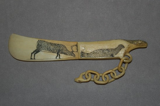 Hearst Museum object titled Letter opener, accession number 2-1368, described as Made of ivory.  Carved animal head at end of handle.  Reindeer incised and darkened on blade.  Incised and darkened seal on one side of handle, weasel on other side.  Pendant chain ending in animal head.