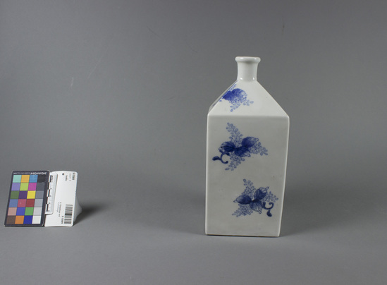 Hearst Museum object titled Bottle, accession number 9-15909, described as 'Bohle' square porcelain bottle w/ rectangular sides, high shoulder formed by flat triangles sloping to narrow round neck w/ round lip.  underglaze blue hand painted motifs of 3 leaves & tiny flowers widely spaced on white ground.  3 3/4" square  8 1/2" high