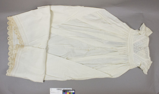 Hearst Museum object 3 of 3 titled Dress, accession number 2-63483, described as Christening Gown: White plain weave cotton gown. Long, full skirt gathered on eyelet waistband. Wide-necked bodice has hand embroidered eyelet. Materials: Cotton Techniques: Plain weave, embroidery Colors: White Dimensions: 16” waistband; 43” long center back; 35 1/4” hem width. 1878 for William Randolph Sayre, Mrs. Houts’ father. Stains down front and back skirt. Handsewn. Made by Clara Burton of 3976.