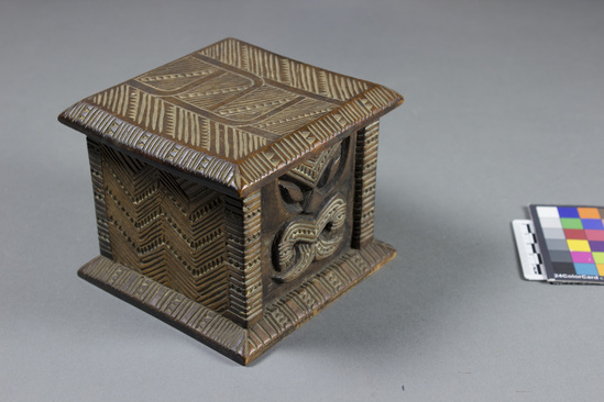 Hearst Museum object 8 of 8 titled Carved wooden box, accession number 11-42799a,b, described as Box and lid, wood, carved in relief, geometric pattern on lid and two sides of box, facial image carved on other two sides of box; tan and brown.