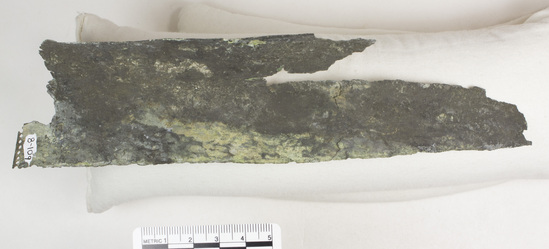 Hearst Museum object 3 of 45 titled Greaves, accession number 8-109, described as Bronze greave and 9 fragments small holes all around edge; serpent and scroll design raised and repousee; greave 41.9 cm long