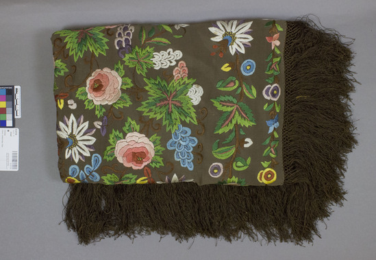 Hearst Museum object titled Shawl, accession number 9-22724, described as brown silk crepe shawl, embroidered with multi-colored flowers and green/brown leaves and stems around all 4 borders.  empty center, with sparse brown, hand knotted fringe on all 4 edges.