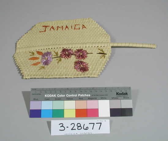 Hearst Museum object titled Woven mat, accession number 3-28677, described as Woven mat with handle; floral pattern and "Jamaica" embroidered in colored straw