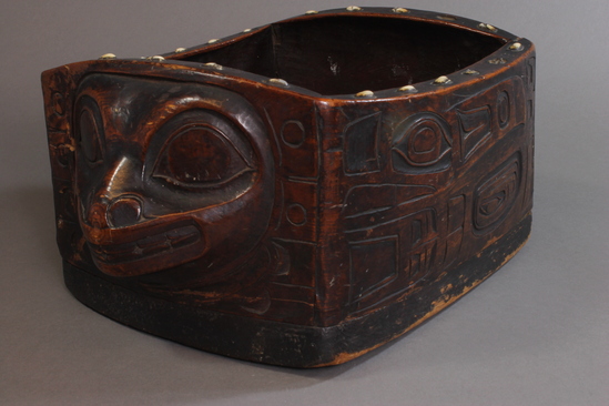 Hearst Museum object titled Box, accession number 2-33830, described as Carved cedar box; sixk' (six = box, k' = "small"); steamed and bent. The design represents a killer whale. Ceremonial dish, lined with skunk cabbage leaves, to contain valuable oil or some other valuable material. Used at totem pole erections and at burials. (Charles Brown, 1964)