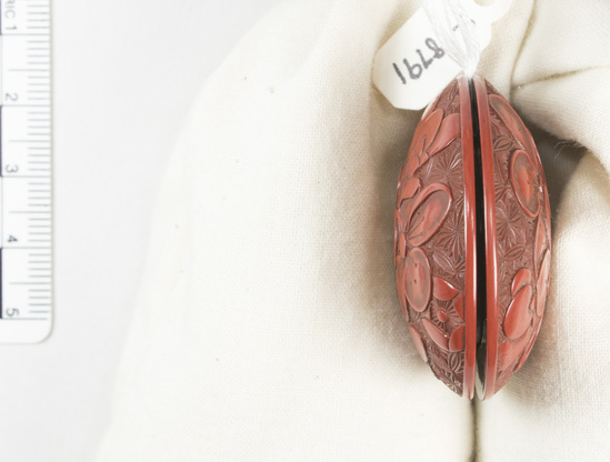 Hearst Museum object 3 of 6 titled Netsuke, accession number 9-18791, described as Netsuke; wood, two-piece, discoidal shape; floral design on both exteriors, halves nested together; metal ring inside center of one half, hole through center on other half; red; Manju style; Dia. 4.0 cm