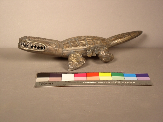 Hearst Museum object titled Caiman figurine, accession number 16-20415, described as Chimu style caiman with big teeth and serpents (2) on each side of snout. 4 loose round discs attached by rings on each side.