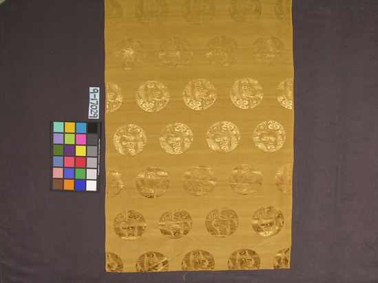 Hearst Museum object titled Textile, accession number 9-17029, described as Silk cloth. Lengthy piece, rolled up. Damask, gold on gold with repeated dragon design. 76 1/2cm wide