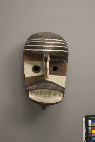 Hearst Museum object titled Mask, accession number 5-16136, described as Ibo Mask. carved, painted wood. deep carved features, prominent lips and teeth. knob below chin. painted black/white/yellow/red assymetrically. 4 white bands around forehead. 8 holes around edge for attachment of a drape. Conservation: Cracked chin, forehead. Ibo Mask (Udi 2, 800, 1945). "Picasso," medium , black, white, yellow and red; asymetrical. cracked.