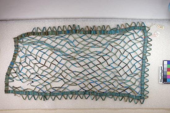 Hearst Museum object titled Net, accession number 5-10316, described as Bead net; tubular blue and green faience beads and modern string; irregular rectangle funerary net; small disk beads of white, red-brown and black faience, stone and bone (?). Solid border of parallel tubular faience beads; interior open net of tubular beads in diamond pattern with similar disk beads at some intersections. Outside of border are tubular beads strung in sawtooth pattern on three sides. Has antiquities service ticket dated 1906. Length 44.5 cm, max. width 26.5 cm.