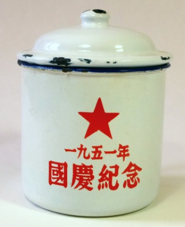 Hearst Museum object titled Mug with lid, accession number 9-23892a,b, described as Enamel mug with lid. The white ground features a red five-pointed star and a red inscription saying “Commemoration for 1951 National Day” (一九五一年 國慶紀念 yi jiu wu yi nian Guoqing ji’nian). The rim is decorated with a dark blue bowstring; the handle is partially painted in the same color. The lid is a replacement by the vendor Ms. Zheng. Acquisition Data: Zheng Haisheng, Baoguosi, Beijing, with Eliza King. RMB 300. 2010-09-02.