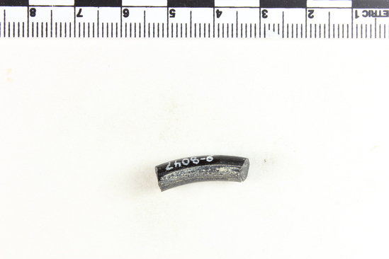 Hearst Museum object 3 of 6 titled Bracelet fragment, accession number 9-8047, described as Glass bracelet frag.; opaque black, curved rod w/ pale blue-green longitudinal bands; 20 x 6 mm.